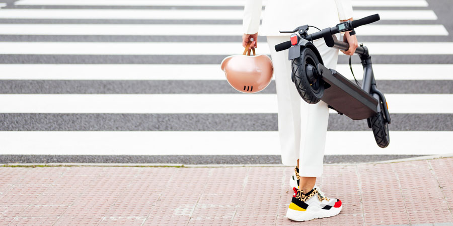 woman crossing with helmet and electric scooter